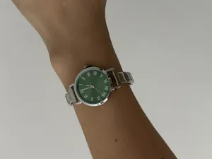 Detailopname van een dameskwartshorloge met groene wijzerplaat en zilveren stalen band.