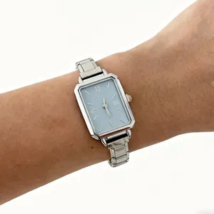 Detail view of an elegant silver steel band quartz watch with a light blue dial.
