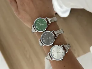 Three modular stainless steel watches with green, grey, and silver dials on wrist