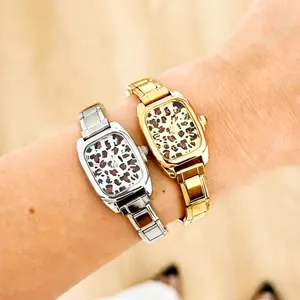 Close-up van gouden en zilveren vierkante horloges met luipaardprint om een pols.