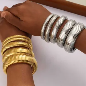 Nahaufnahme von goldenen und silbernen gerippten Edelstahl-Stretcharmbändern.