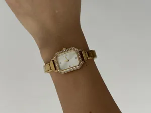 Gros plan d'une élégante montre à quartz dorée pour femme avec strass au poignet