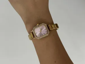 Vue détaillée d'une montre à quartz carrée dorée avec cadran rose portée au poignet