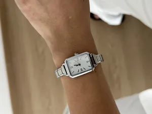 Close-up of a classic silver rectangular quartz watch with stainless steel strap on wrist