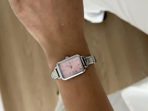 Detailed close-up of a women's silver steel quartz watch with a pink dial on wrist.