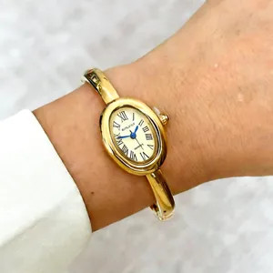 Elegante goudkleurige quartz dameshorloge met ovale wijzerplaat en Romeinse cijfers design