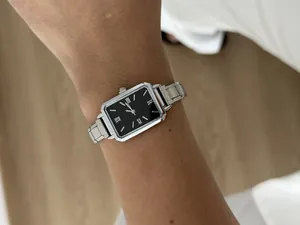 Detail shot of a classic silver steel strap women's watch with a black square dial