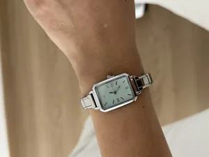 Close-up view of an elegant silver rectangular women's quartz watch worn on a wrist