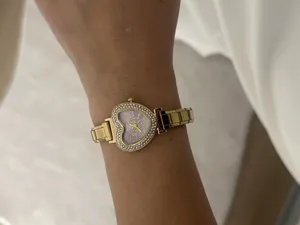 Detailed view of a gold heart-shaped crystal watch worn on a wrist with a modular band