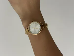 Detailopname van goudkleurig dameshorloge met modulaire roestvrijstalen band