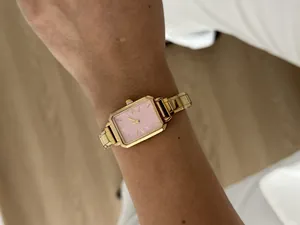 Close-up of elegant ladies' quartz watch with pink dial and golden steel band on wrist
