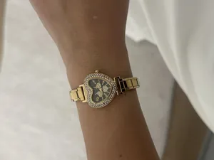 Close-up of a elegant gold heart-shaped watch with rhinestone bezel on a woman's wrist