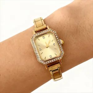 Gros plan d'une élégante montre carrée dorée pour femme avec strass sur un poignet.