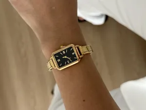 Elegant gold rectangular women's quartz watch featuring a black dial and Roman numerals