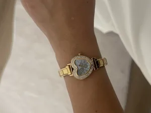 Detail of heart-shaped gold watch with rhinestone bezel and modular steel bracelet