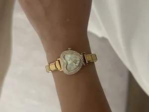 Detail view of an elegant gold heart-shaped watch with a rhinestone bezel on a wrist