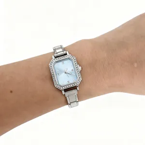 Gros plan d'une montre carrée argentée pour femme avec cadran bleu clair et strass brillants