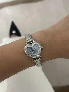 Close-up of a women's heart-shaped wristwatch with rhinestone bezel and blue dial
