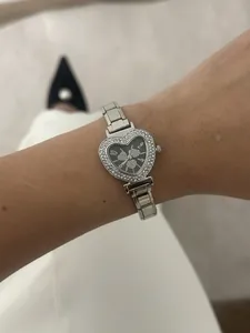 Elegant silver heart-shaped watch with black dial and rhinestone bezel on wrist