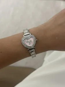 Close-up of heart-shaped women's watch with pink dial and rhinestones on silver band