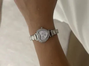 Detail view of silver heart-shaped watch with rhinestone bezel on woman's wrist