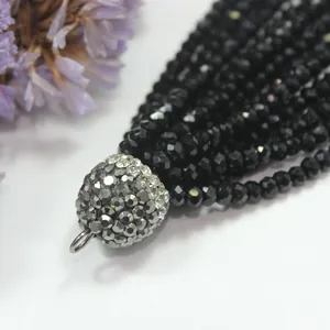 Close-up detail of a black faceted bead tassel with a sparkling rhinestone-encrusted cap