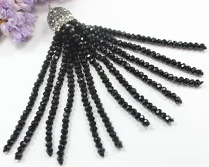 Macro detail of black faceted crystal bead tassel pendant with sparkling rhinestone cap.