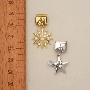 Detailed macro view of gold and silver star Italian charms beside a ruler for scale