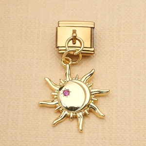 Close-up of golden Italian charm with dangling sun moon motif and pink rhinestone