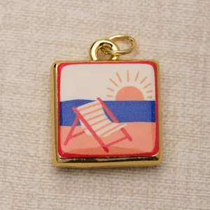 Macro view of square gold-framed copper pendant featuring a colorful beach sunset illustration