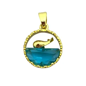 Detail van gouden oceaan hanger met blauwe geslepen steen en een springende walvis