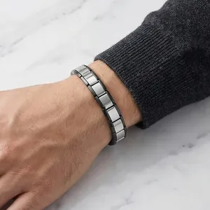 Close-up of a stainless steel Italian modular charm bracelet worn on a male wrist.