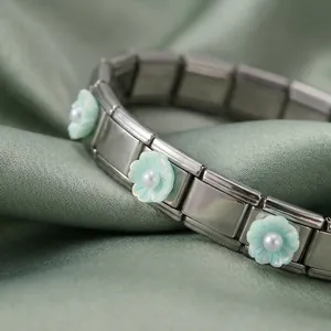 Vista macro de pulsera italiana de acero inoxidable con flores verdes y perlas