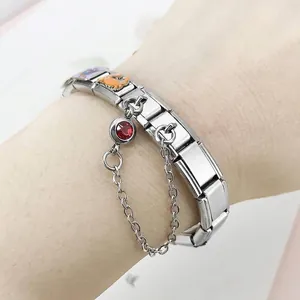 Detailed close-up of a stainless steel Italian charm bracelet with red birthstone charm