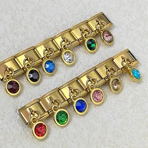 Primo piano di un bracciale modulare italiano in acciaio dorato con pietre natali colorate.