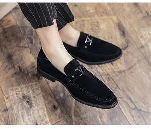 Detailed close-up of men's black suede loafers with a stylish decorative metal V buckle