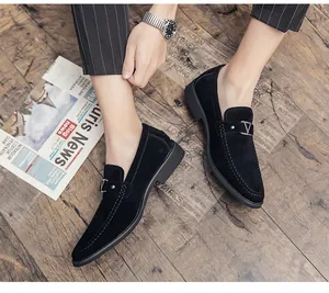 Detailed view of elegant black suede pointed loafers featuring a metal V buckle on wood floor