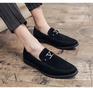 Close-up of men's black suede loafers featuring a stylish silver V-buckle