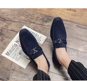 Macro view of blue suede loafers with metallic buckle detailing on wooden floor
