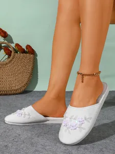 Dettaglio pantofole in camoscio bianco con paillettes floreali e ricami rifiniti