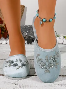 Vista dettagliata delle pantofole in velluto azzurro da donna con fiori di paillettes