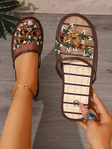 Detailed view of embroidered mesh mule slippers with flat sole and floral accents