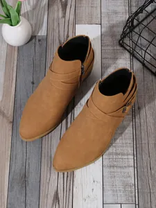 Detailed top-down view of tan pointed-toe Chelsea boots with cross-strap buckles.