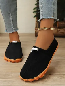 Nahaufnahme von schwarzen atmungsaktiven Barfuß-Sneakern für Damen mit orangefarbener Sohle.