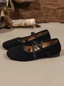 Vista dettagliata delle ballerine Mary Jane in camoscio nero con cinturini incrociati.