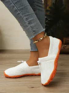 Detailansicht weißer Fly-Knit Barfußschuhe mit rutschfester orangefarbener Sohle.
