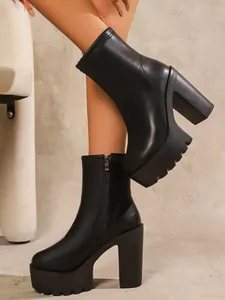 Close-up detail of black platform ankle boots with chunky high heels and lug soles.