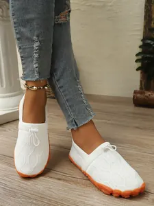 Detailansicht der weißen, atmungsaktiven Barfuß-Sneaker mit orangefarbener Gummisohle