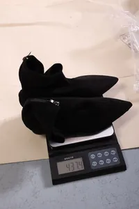 Schwarze, spitze Wildleder-Socken-Stiefel auf einer Waage mit einem Gewicht von 437,4 g