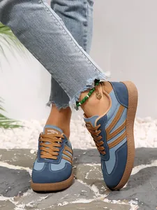 Detailed close-up view of retro blue and brown color-block women's sneakers worn on feet outdoors